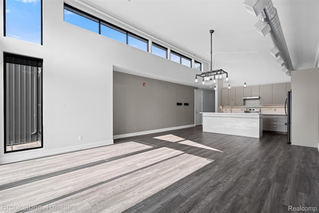 1711 Livernois St Unit 7, Ferndale, MI 48220 - unfurnished living room featuring a high ceiling, dark wood finished floors, healthy amount of natural light, a chandelier, and baseboards