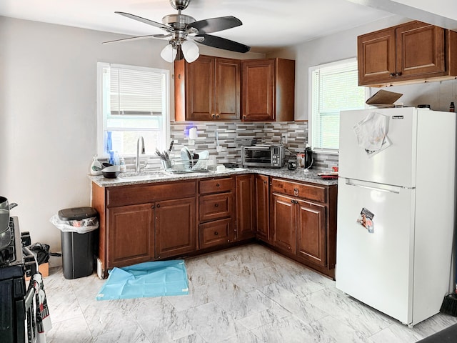 19549 Melrose Ave, Southfield, MI 48075 - kitchen featuring freestanding refrigerator, a ceiling fan, decorative backsplash, light stone countertops, and brown cabinetry