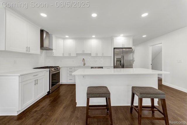1285 Ruffner Ave, Birmingham, MI 48009 - kitchen with appliances with stainless steel finishes, wall chimney range hood, a breakfast bar area, white cabinetry, and recessed lighting