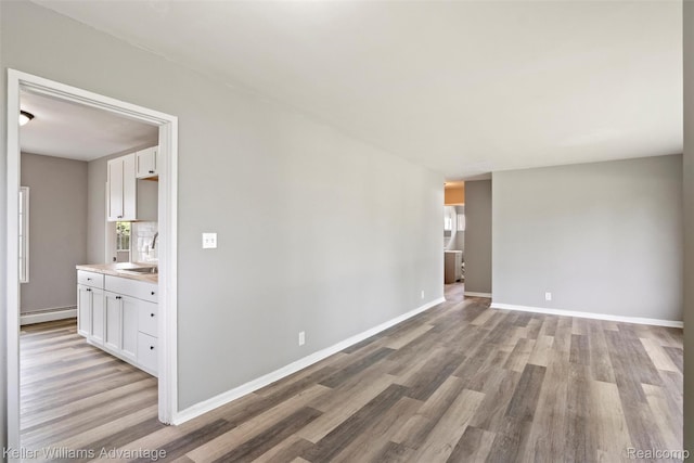 26315 Lehner St, Roseville, MI 48066 - unfurnished room featuring a sink, light wood-type flooring, a baseboard heating unit, and baseboards