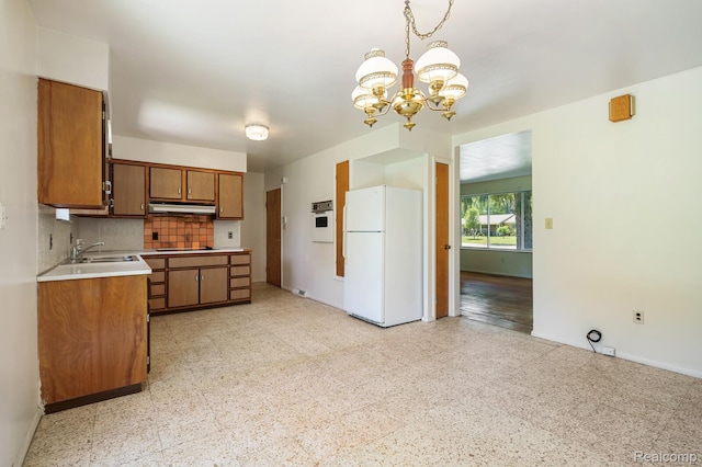 1312 N Bielby St, Waterford, MI 48328 - kitchen with freestanding refrigerator, a chandelier, brown cabinetry, under cabinet range hood, and a sink