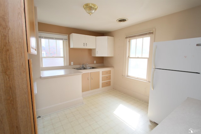 624 Waterloo Ave, Monroe, MI 48161 - kitchen featuring freestanding refrigerator, light flooring, a sink, light countertops, and white cabinetry