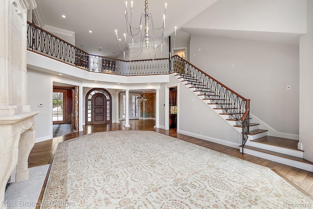2921 Turtle Pond Ct, Bloomfield Hills, MI 48302 - entrance foyer featuring decorative columns, wood finished floors, a chandelier, stairs, and a high ceiling