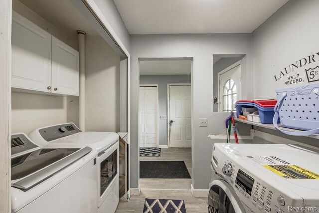 2475 S Ortonville Rd S, Ortonville, MI 48462 - laundry area featuring separate washer and dryer, light wood-style floors, cabinet space, and baseboards