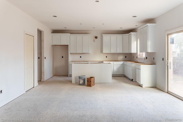 3201 Roma Ct, Wixom, MI 48393 - kitchen with a kitchen island, light carpet, and white cabinets