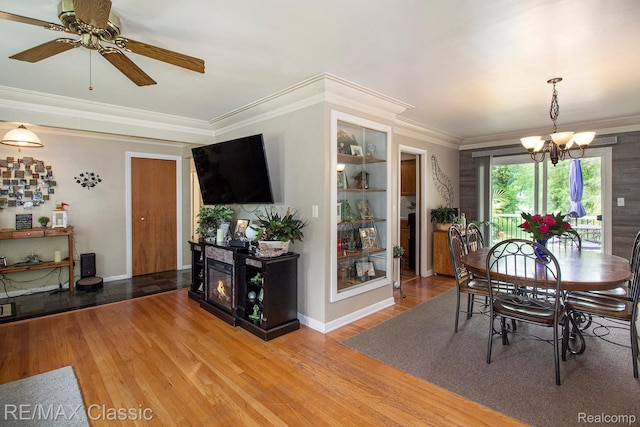 38 Meadowview Dr, Howell, MI 48843 - dining space with a chandelier, wood finished floors, crown molding, a glass covered fireplace, and ceiling fan