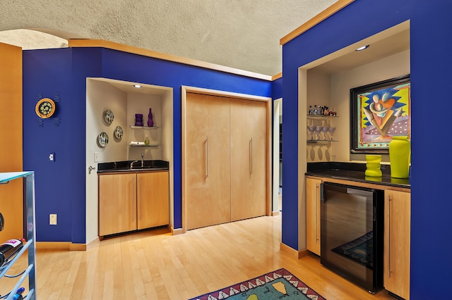 2755 N 9th St, Kalamazoo, MI 49009 - interior space featuring beverage cooler, light wood-type flooring, dark countertops, a textured ceiling, and baseboards