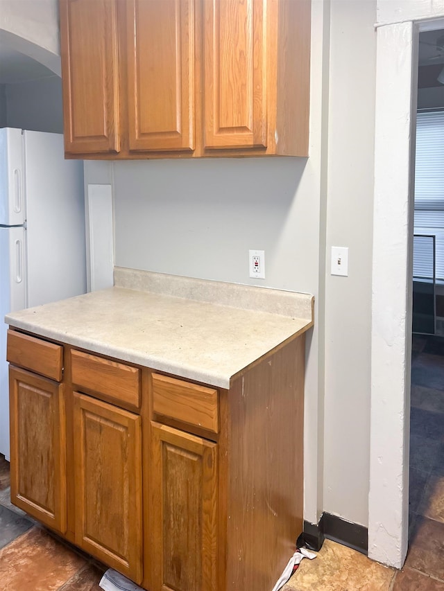 611 E Mount Hope Ave, Lansing, MI 48910 - kitchen featuring freestanding refrigerator, light countertops, arched walkways, and brown cabinetry
