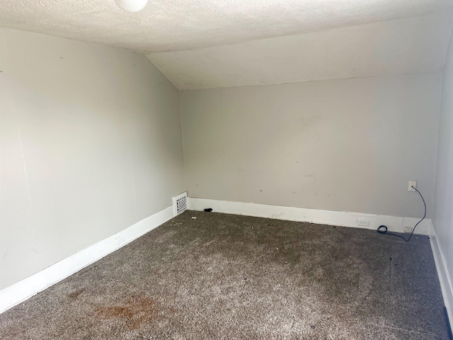 611 E Mount Hope Ave, Lansing, MI 48910 - spare room featuring carpet flooring, lofted ceiling, a textured ceiling, and baseboards