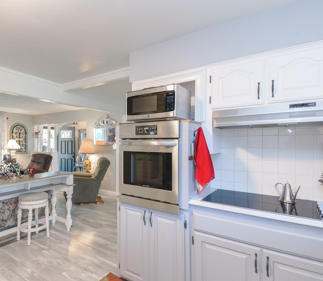 4143 Browning Dr, Saint Joseph, MI 49085 - kitchen featuring appliances with stainless steel finishes, under cabinet range hood, white cabinetry, open floor plan, and backsplash