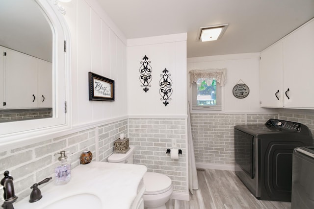 4143 Browning Dr, Saint Joseph, MI 49085 - bathroom with washing machine and clothes dryer, toilet, a sink, wood finished floors, and decorative backsplash