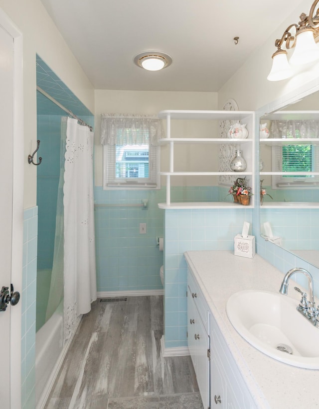 4143 Browning Dr, Saint Joseph, MI 49085 - full bathroom with vanity, tile walls, wood finished floors, shower / bathtub combination with curtain, and toilet