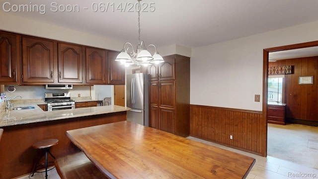6624 Wellesley Ter, Clarkston, MI 48346 - kitchen featuring appliances with stainless steel finishes, wooden walls, a chandelier, decorative light fixtures, and light stone counters