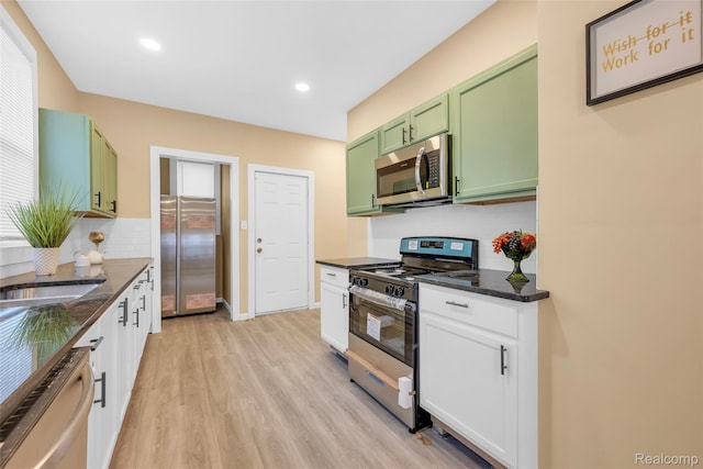 8857 Charlevoix St, Detroit, MI 48214 - kitchen with appliances with stainless steel finishes, green cabinets, light wood finished floors, decorative backsplash, and dark stone countertops