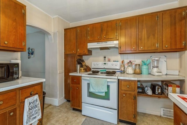 927 Harrison Ave, Saint Joseph, MI 49085 - kitchen with under cabinet range hood, white electric range oven, light countertops, brown cabinetry, and crown molding
