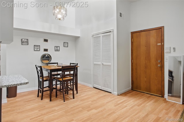1332 Shoemaker Dr Unit 1332, Belleville, MI 48185 - dining area with a high ceiling, light wood-style floors, a chandelier, and baseboards