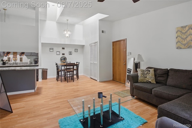 1332 Shoemaker Dr Unit 1332, Belleville, MI 48185 - living room with a towering ceiling, light wood finished floors, a chandelier, ceiling fan, and baseboards