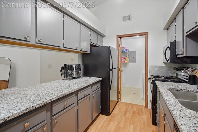 1332 Shoemaker Dr Unit 1332, Belleville, MI 48185 - kitchen featuring black appliances, light wood-style floors, electric panel, gray cabinets, and baseboards