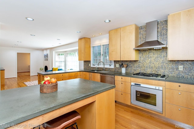 8019 Concord Rd, Huntington Woods, MI 48070 - kitchen featuring wall chimney exhaust hood, appliances with stainless steel finishes, light wood-style flooring, a peninsula, and dark countertops