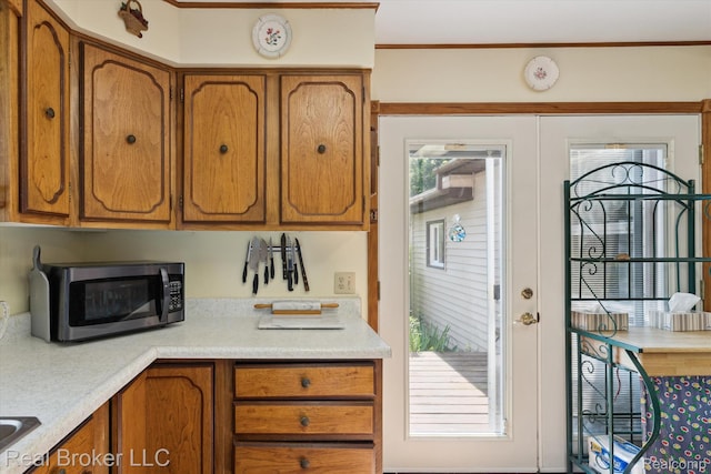 5740 M 66, East Leroy, MI 49051 - kitchen with stainless steel microwave, brown cabinetry, light countertops, and crown molding