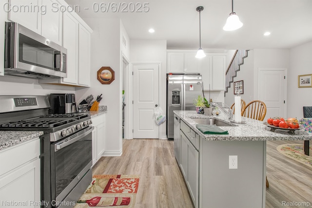 11801 Hines Place Dr, Livonia, MI 48150 - kitchen featuring appliances with stainless steel finishes, a sink, light wood finished floors, white cabinetry, and a kitchen island with sink