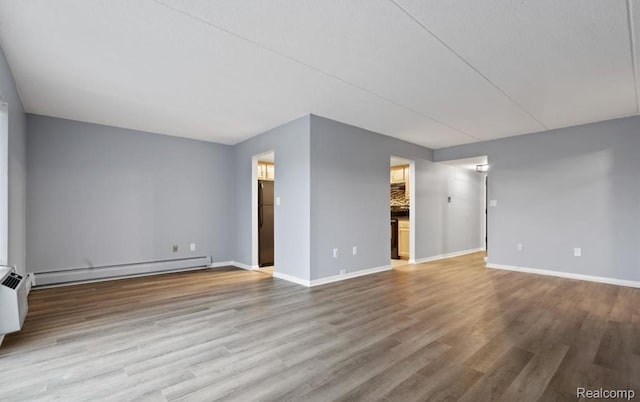 35300 Woodward Ave Unit 408, Birmingham, MI 48009 - unfurnished living room with a baseboard heating unit, baseboards, and wood finished floors
