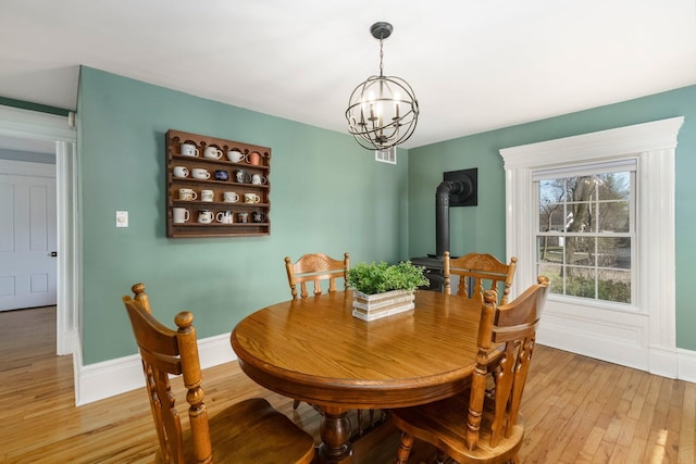 46860 Shelby Rd, Michigan, MI 48317 - dining room featuring a wood stove, light wood-style flooring, a chandelier, and baseboards