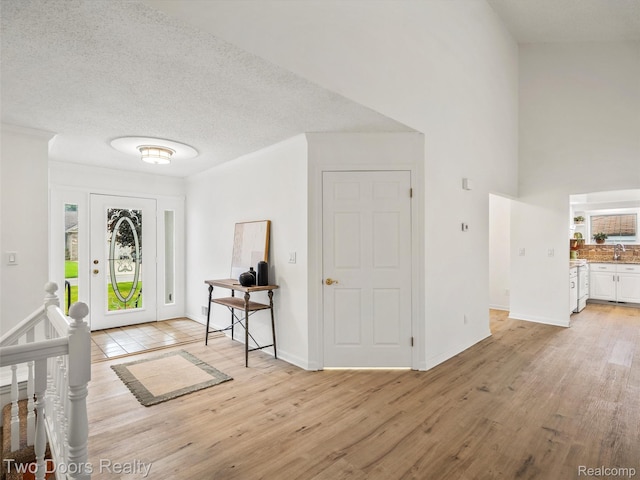 53020 Wolf Dr, Shelby Twp, MI 48316 - entryway with light wood-type flooring, plenty of natural light, baseboards, a towering ceiling, and a textured ceiling