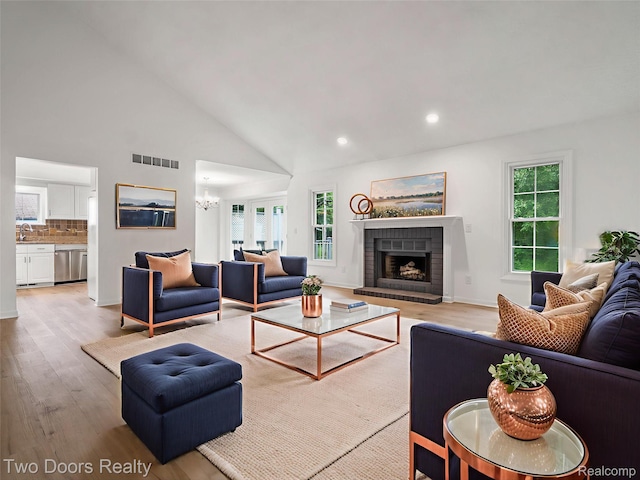 53020 Wolf Dr, Shelby Twp, MI 48316 - living room featuring wood finished floors, a chandelier, a fireplace, recessed lighting, and high vaulted ceiling