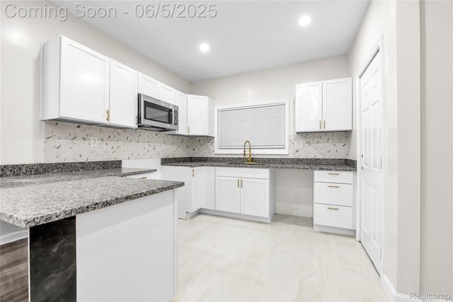 14953 Winthrop St, Detroit, MI 48227 - kitchen featuring a sink, stainless steel microwave, decorative backsplash, white cabinets, and recessed lighting