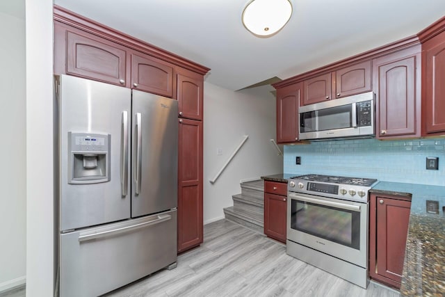 392 Woodfield Square Ln, Brighton, MI 48116 - kitchen featuring stainless steel appliances, decorative backsplash, dark stone counters, light wood finished floors, and reddish brown cabinets