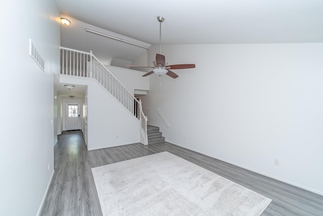 392 Woodfield Square Ln, Brighton, MI 48116 - unfurnished living room featuring wood finished floors, stairs, ceiling fan, baseboards, and lofted ceiling