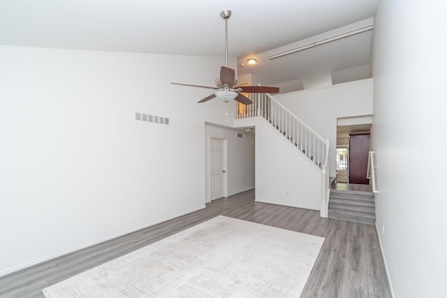 392 Woodfield Square Ln, Brighton, MI 48116 - unfurnished living room featuring wood finished floors, stairway, a towering ceiling, a ceiling fan, and baseboards