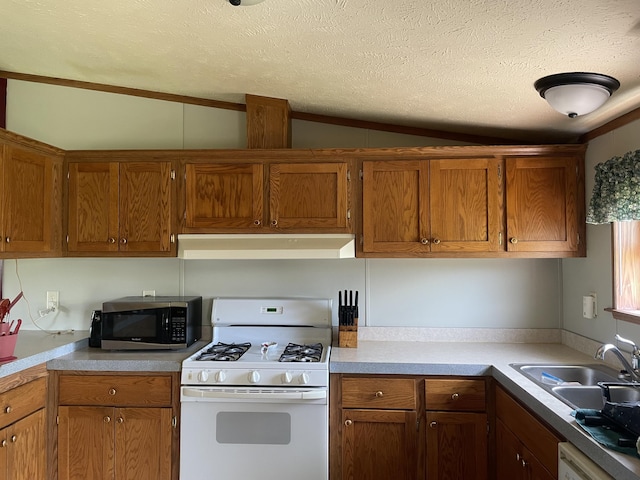 8295 Mccain Rd, Parma, MI 49269 - kitchen featuring white appliances, under cabinet range hood, a textured ceiling, vaulted ceiling, and brown cabinetry