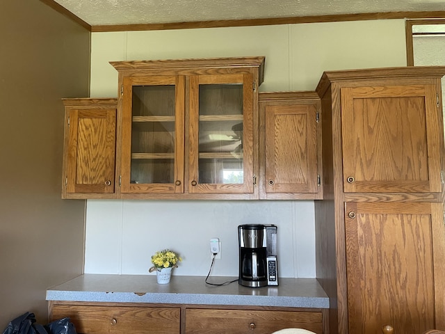 8295 Mccain Rd, Parma, MI 49269 - kitchen featuring brown cabinets, glass insert cabinets, and ornamental molding