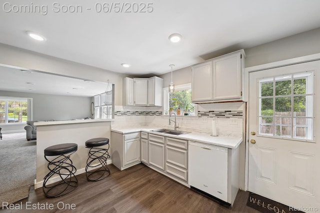 8921 Lake Rd, Grosse Ile, MI 48138 - kitchen featuring white dishwasher, a sink, a peninsula, light countertops, and dark wood finished floors