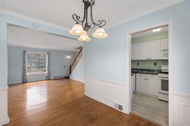22953 Allen Rd, Saint Clair Shores, MI 48080 - unfurnished dining area with light wood-style floors, stairs, crown molding, a wainscoted wall, and a chandelier
