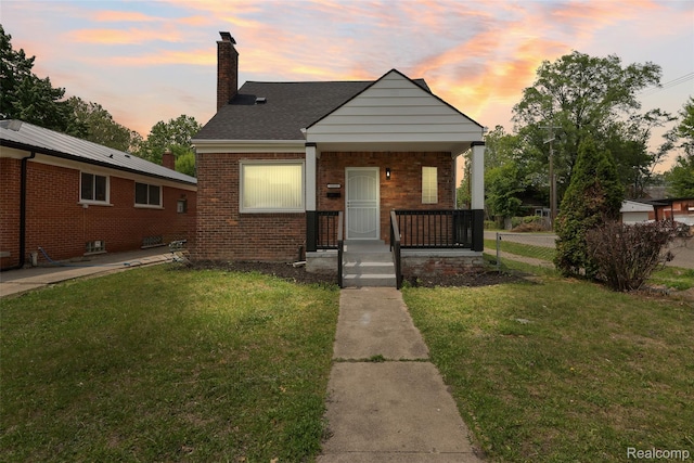 19215 Winthrop St, Dearborn, MI 48235 - bungalow with a chimney, a front yard, covered porch, and brick siding
