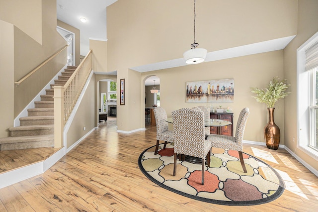 6533 Cannon Farms Dr NE, Rockford, MI 49341 - dining area featuring arched walkways, wood-type flooring, healthy amount of natural light, and a towering ceiling