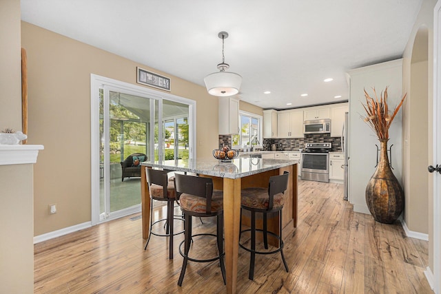 6533 Cannon Farms Dr NE, Rockford, MI 49341 - kitchen featuring appliances with stainless steel finishes, a breakfast bar, white cabinetry, light wood-type flooring, and recessed lighting
