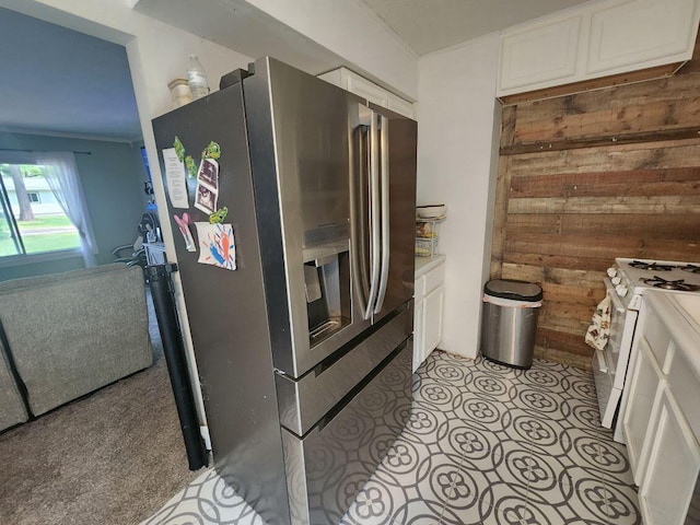 661 W Michigan Rd, Twin Lake, MI 49457 - kitchen with stainless steel fridge, white range with gas cooktop, white cabinetry, wooden walls, and light countertops
