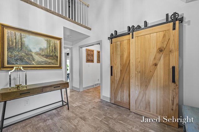 6872 Forest Valley Dr SE, Grand Rapids, MI 49546 - entryway with a barn door, wood finished floors, a high ceiling, and baseboards
