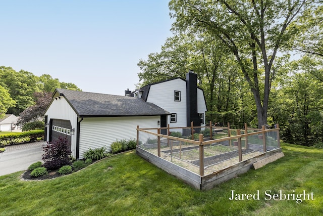 6872 Forest Valley Dr SE, Grand Rapids, MI 49546 - view of side of home featuring a chimney, a yard, roof with shingles, a garden, and a garage