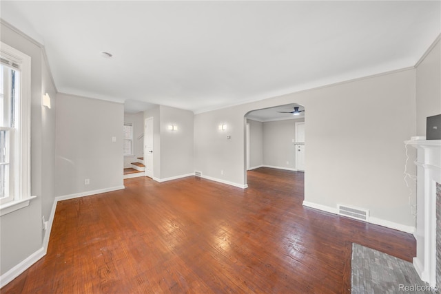 3951 Devonshire Rd, Detroit, MI 48224 - unfurnished living room with wood-type flooring, arched walkways, a fireplace, baseboards, and ceiling fan