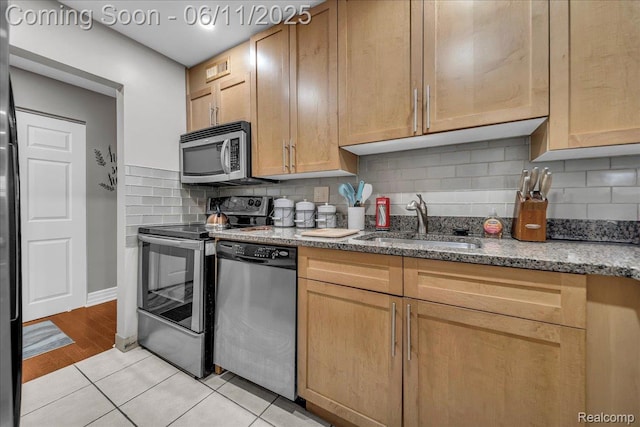 1001 W Jefferson Ave Unit 2I, Detroit, MI 48226 - kitchen featuring appliances with stainless steel finishes, a sink, light stone countertops, light tile patterned flooring, and backsplash