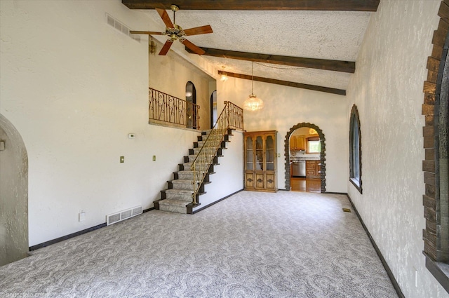5379 N Irish Rd, Davison, MI 48423 - unfurnished living room featuring arched walkways, carpet floors, a ceiling fan, beamed ceiling, and stairs