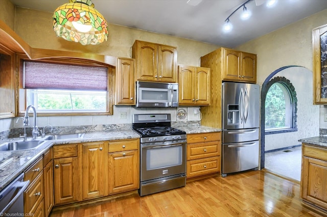 5379 N Irish Rd, Davison, MI 48423 - kitchen with stainless steel appliances, a sink, light wood finished floors, light stone countertops, and a textured wall