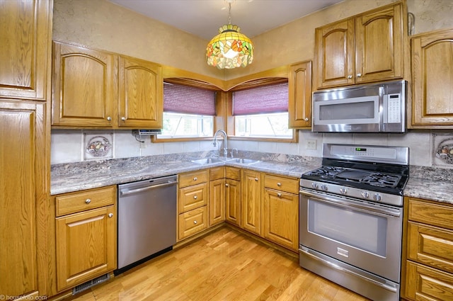 5379 N Irish Rd, Davison, MI 48423 - kitchen featuring stainless steel appliances, a sink, light wood-style flooring, hanging light fixtures, and brown cabinets