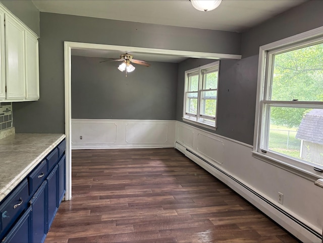 1965 E Kimmel Rd, Jackson, MI 49201 - unfurnished dining area featuring a baseboard radiator, a ceiling fan, dark wood finished floors, and a wainscoted wall