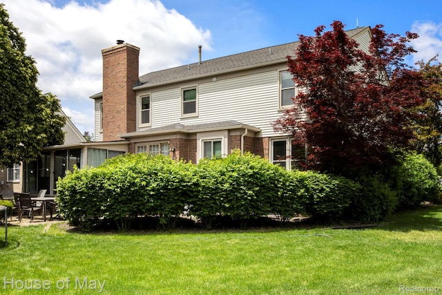 47951 Picadilly Ct, Canton, MI 48187 - rear view of property with a chimney, a yard, brick siding, and a sunroom